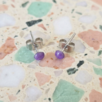 Silver stud earrings with purple beads on a terrazzo background