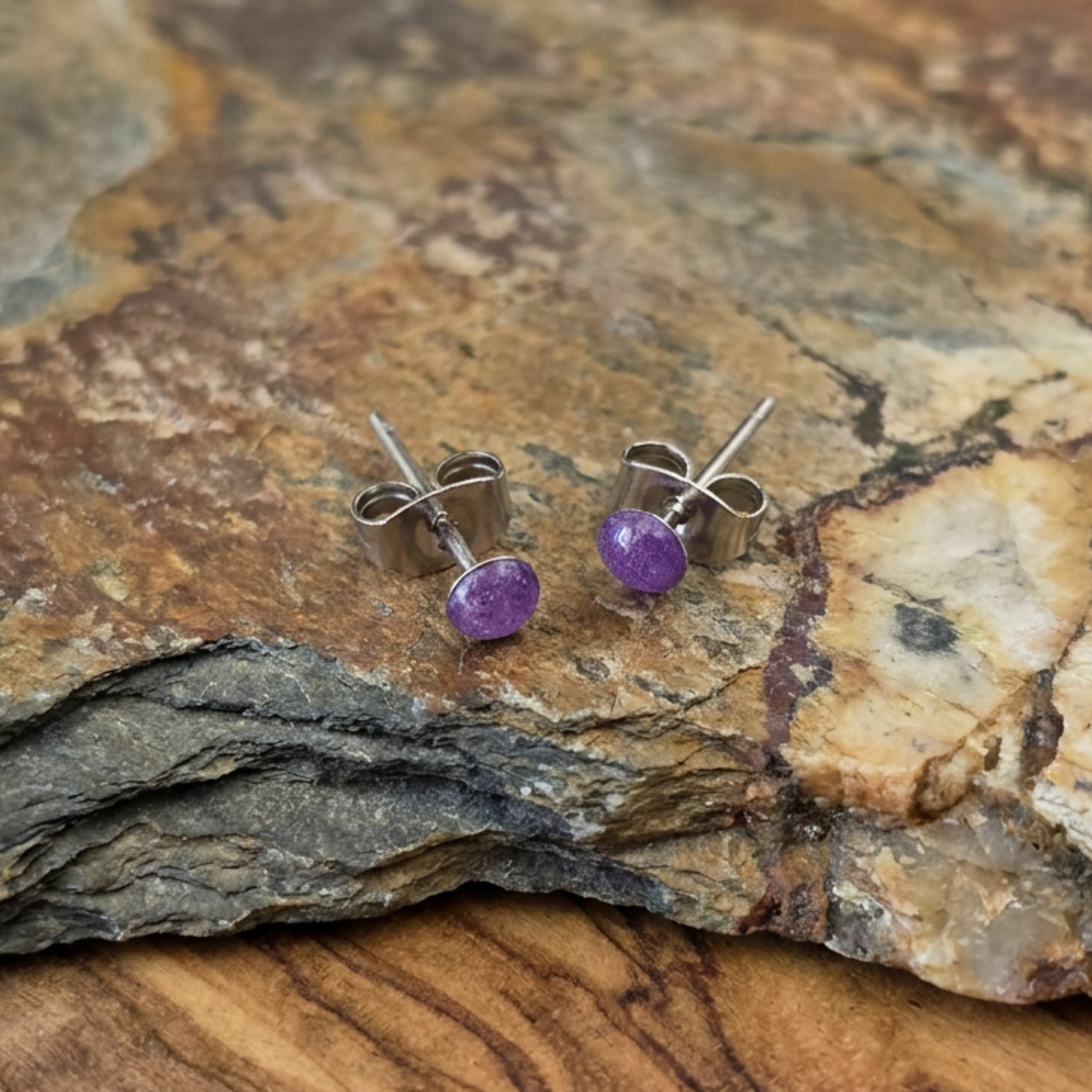 Purple stone stud earrings on a stone surface