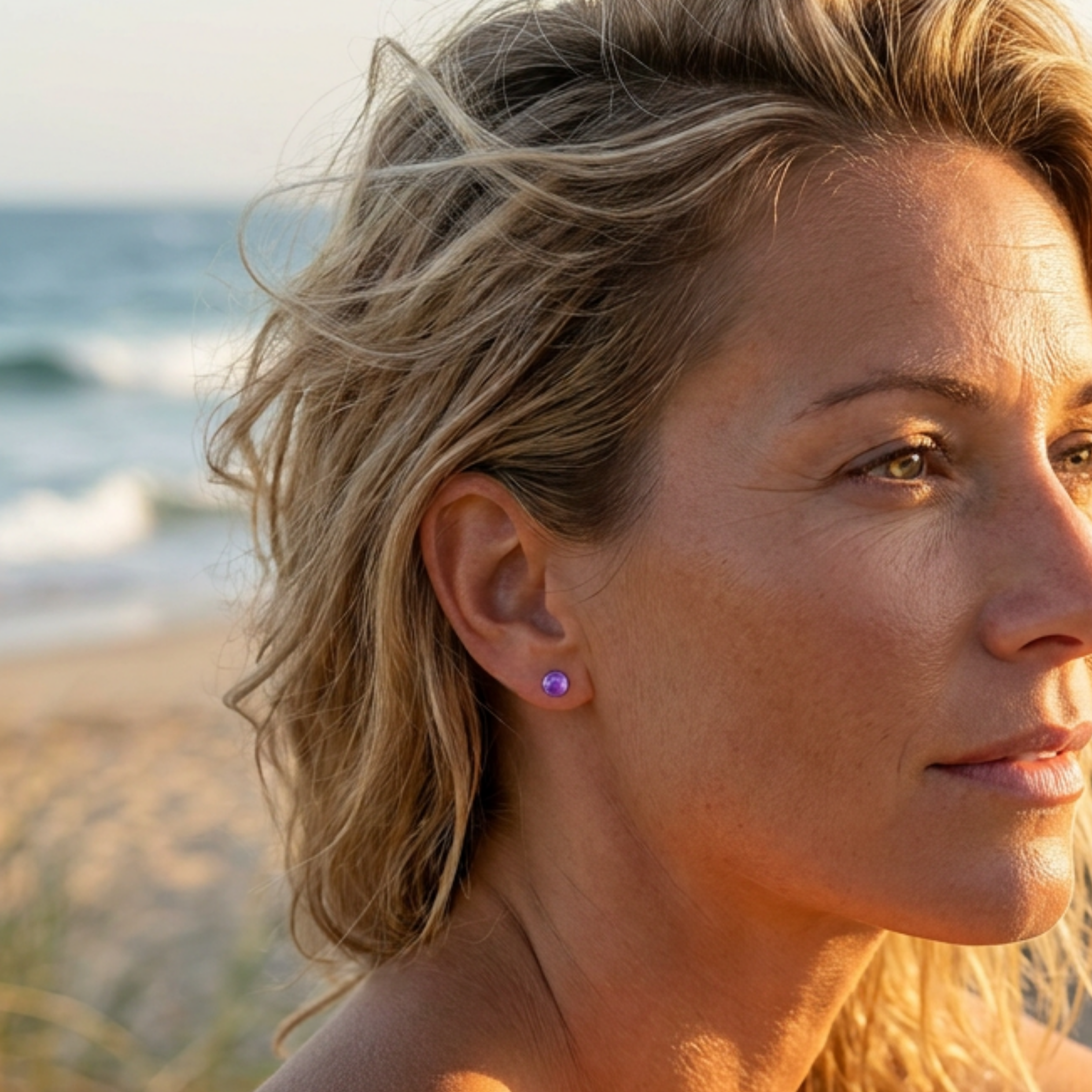 Woman with beach hair and purple earring, sunlit on a beach