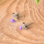 Pair of silver earrings with purple stones on a wooden surface