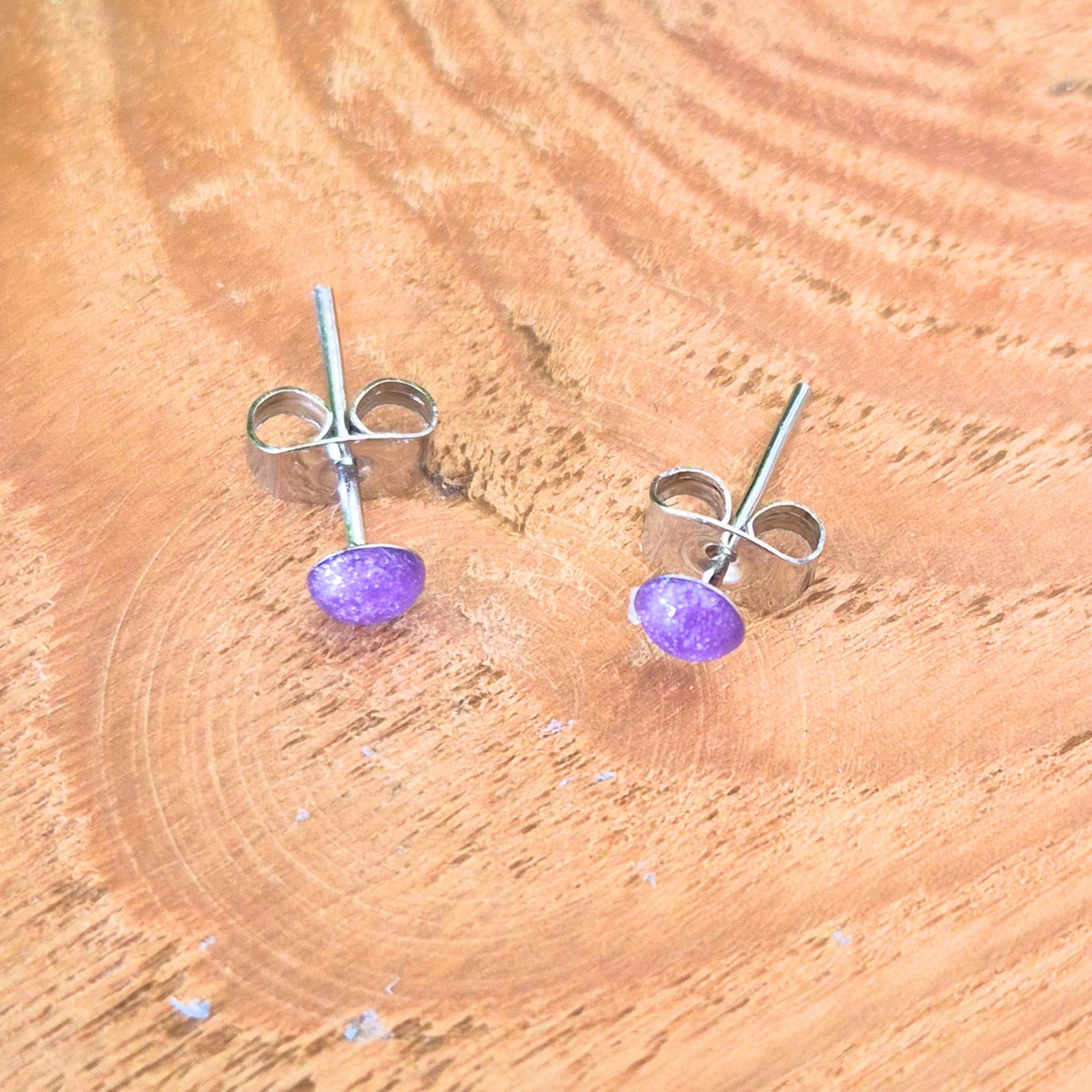 Purple stud earrings on a wooden surface