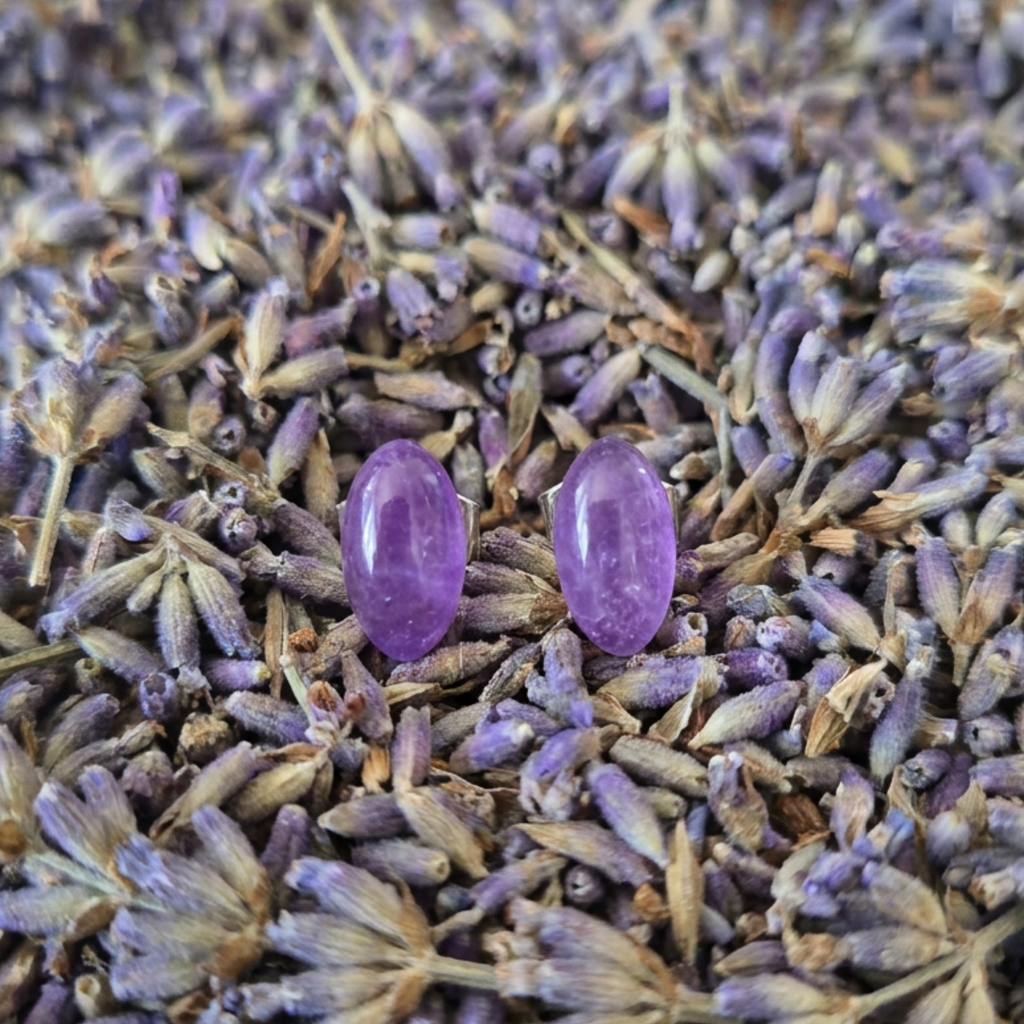 Two purple stud earrings on a bed of dried lavender flowers