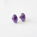 Pair of purple oval stud earrings on a white background