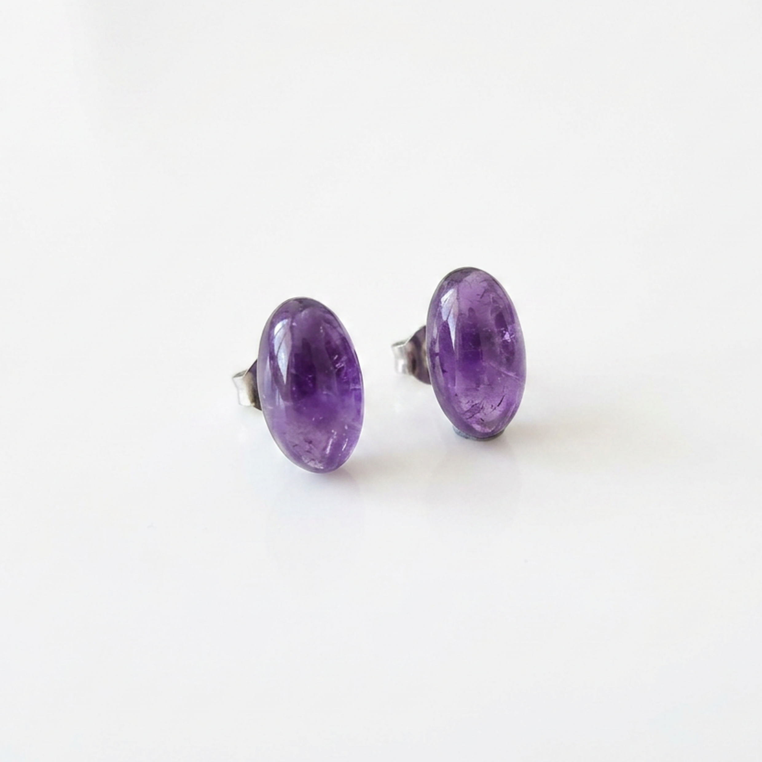 Pair of purple oval stud earrings on a white background