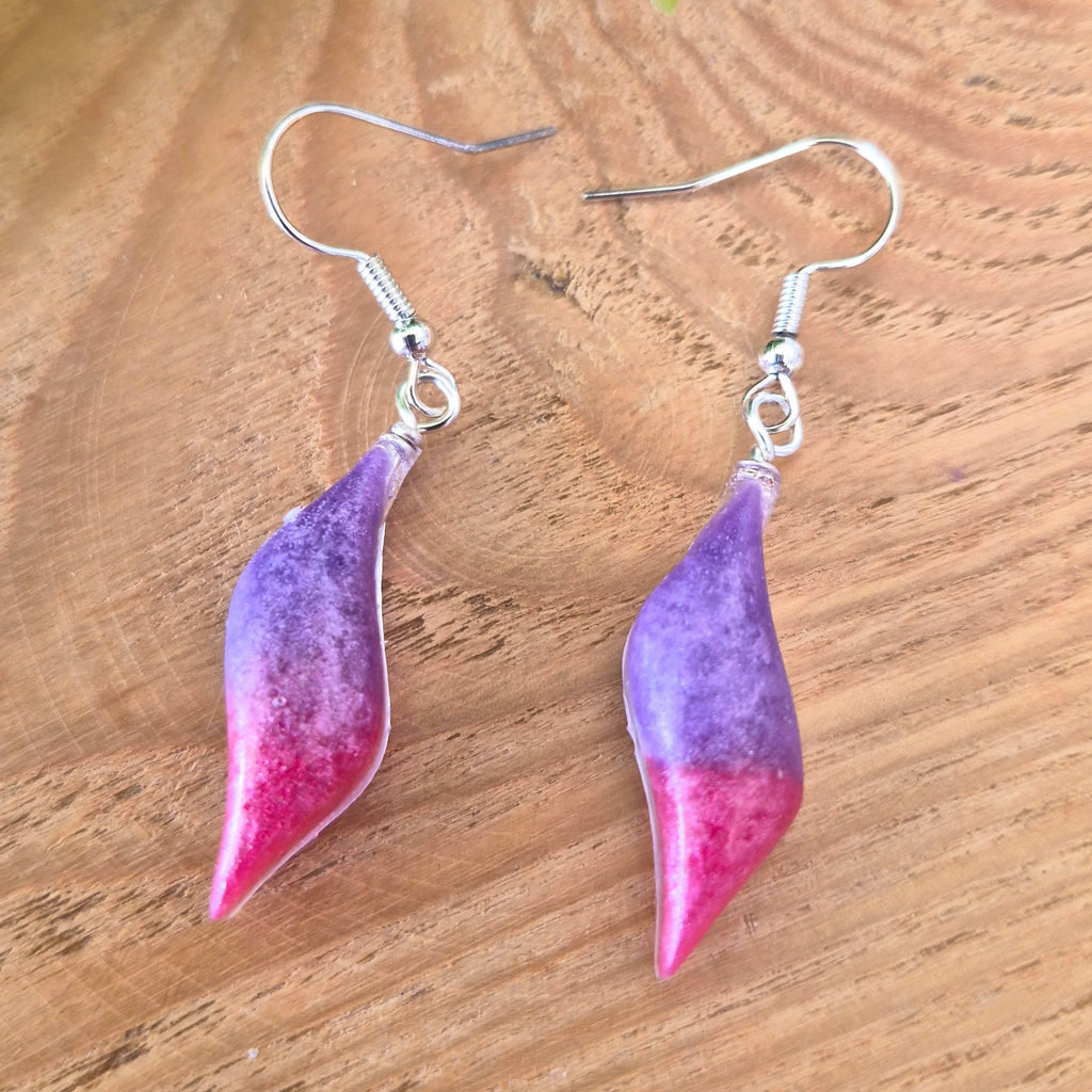 Pink and Purple wavy oval earrings on wood surface