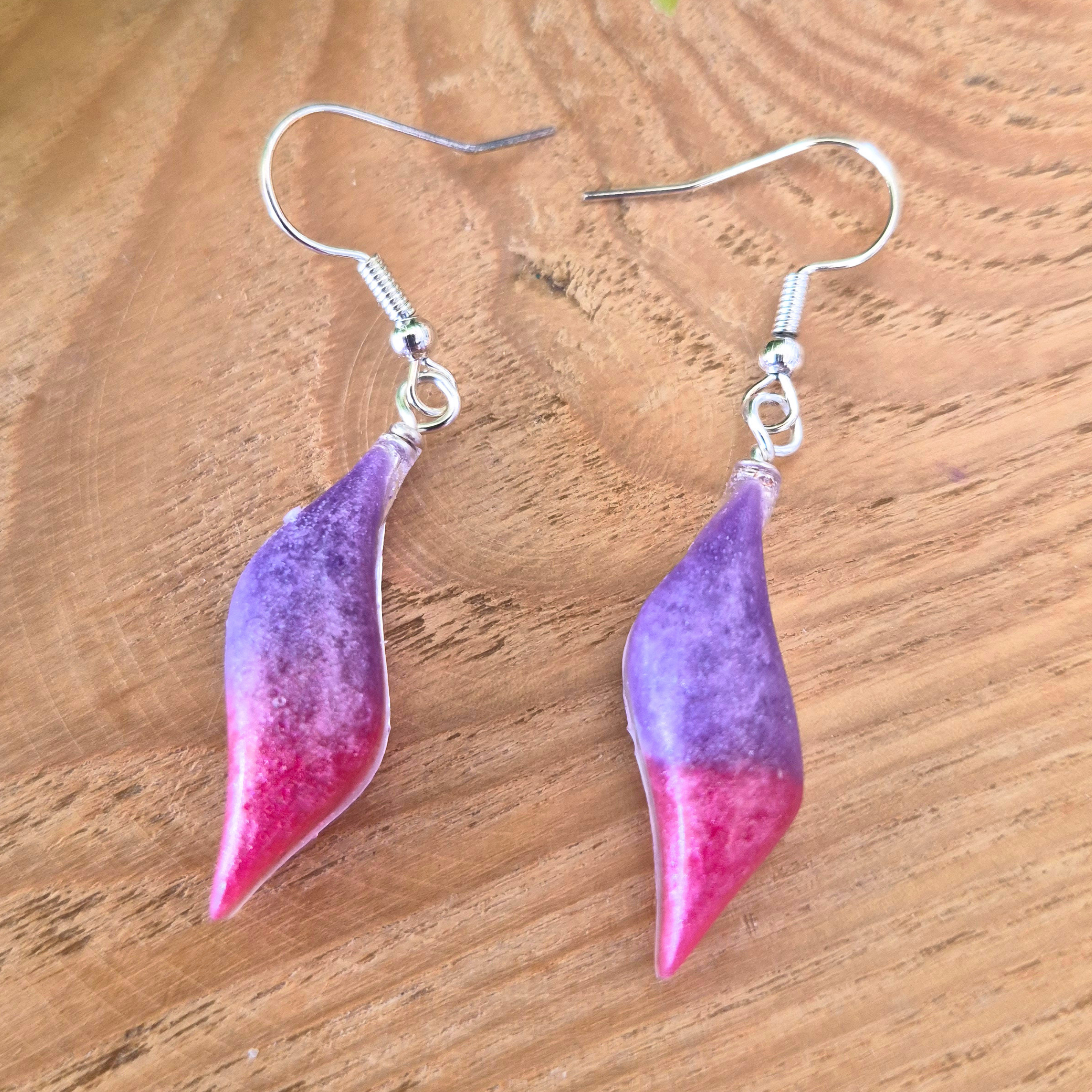 Pink and Purple wavy oval earrings on wood surface