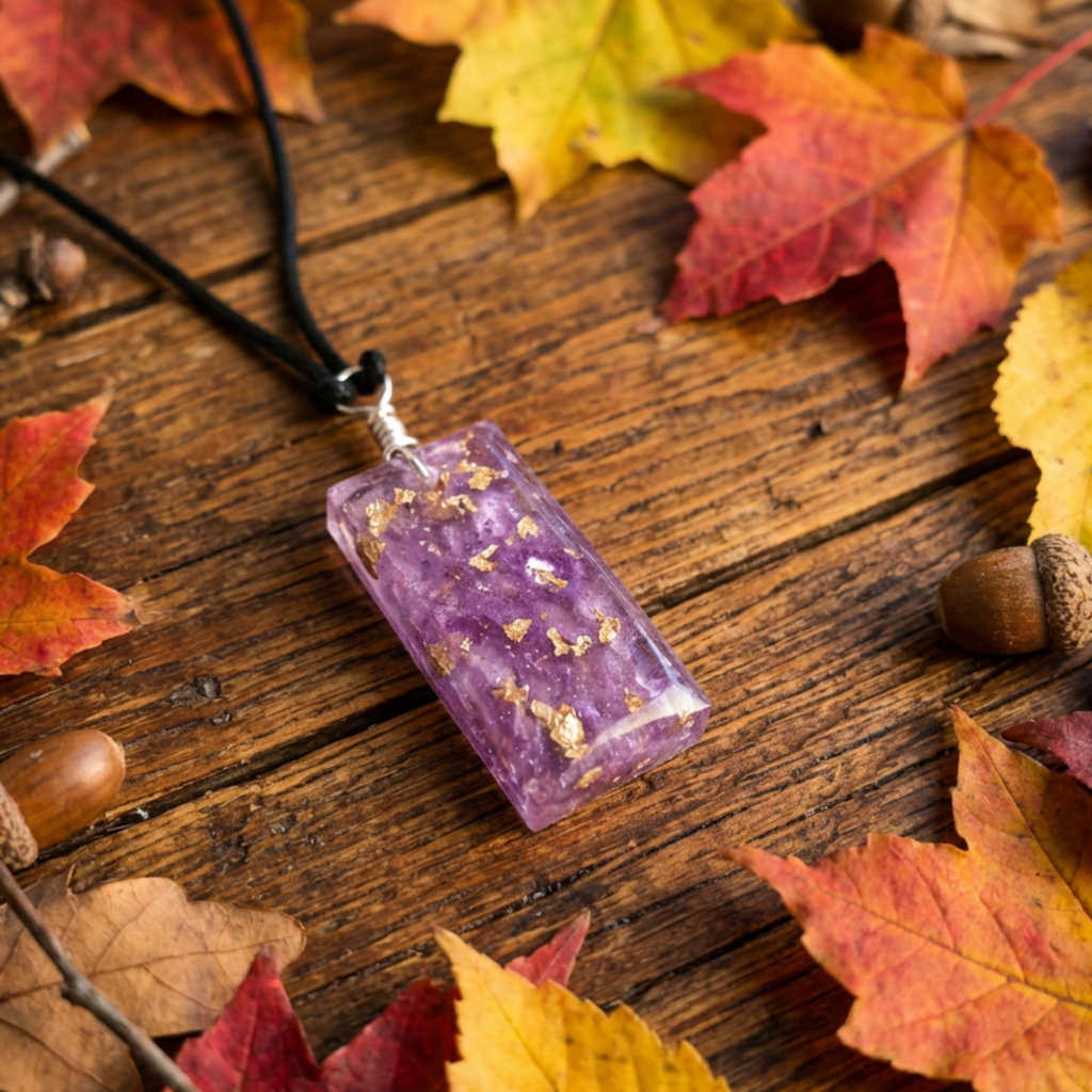 Purple pendant with gold flecks on a wooden surface with autumn leaves