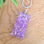 Purple rectangular pendant with gold flecks on a wooden surface