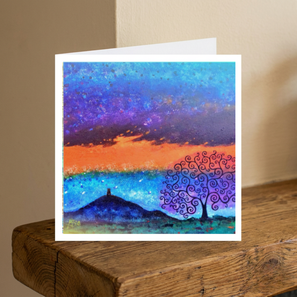 Greeting card with a colourful abstract design featuring a tree and Glastonbury Tor landscape on a wooden surface.
