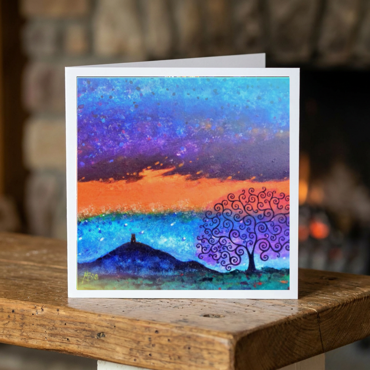 Colourful abstract landscape painting on a wooden surface with a blurred background