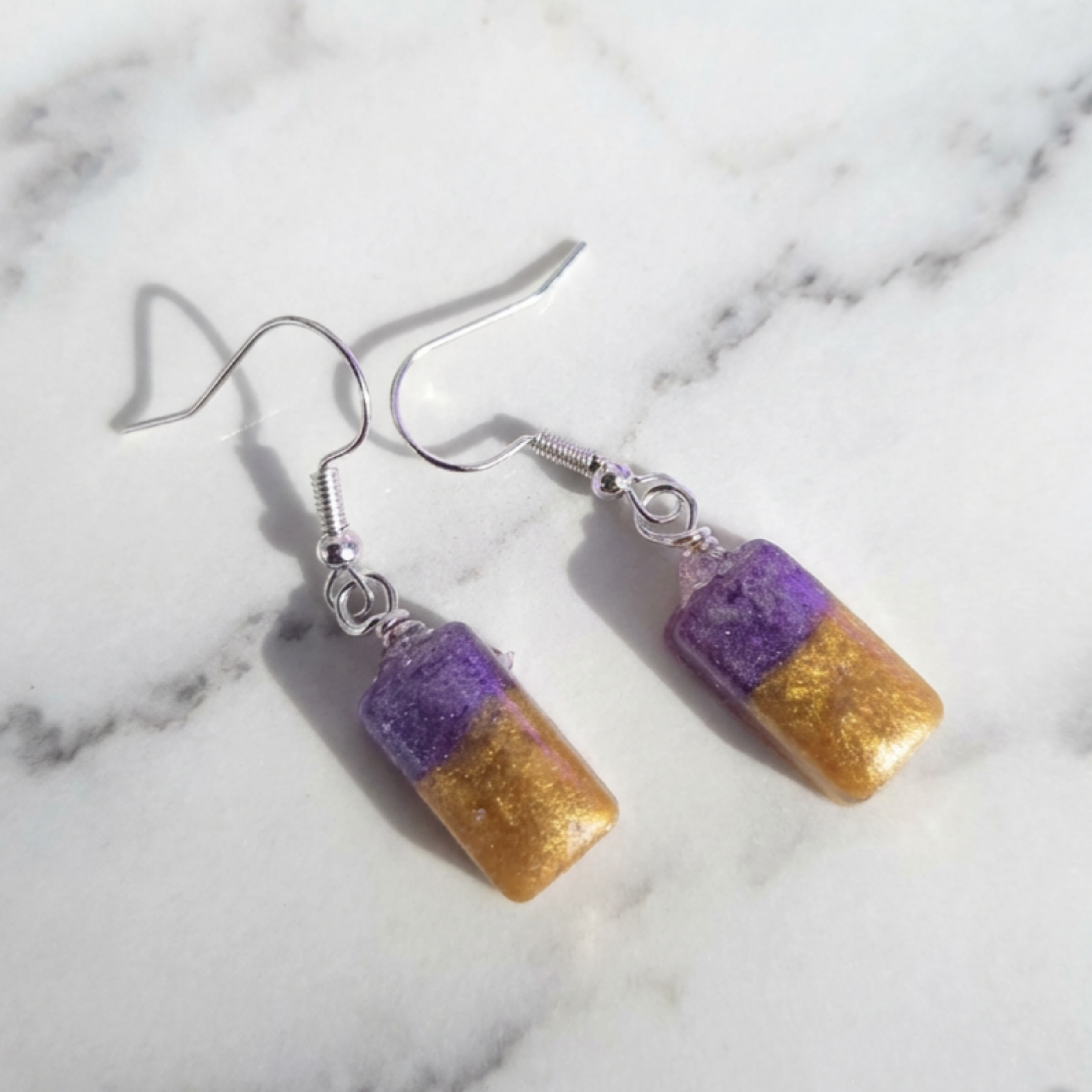 Purple and gold earrings on a marble background