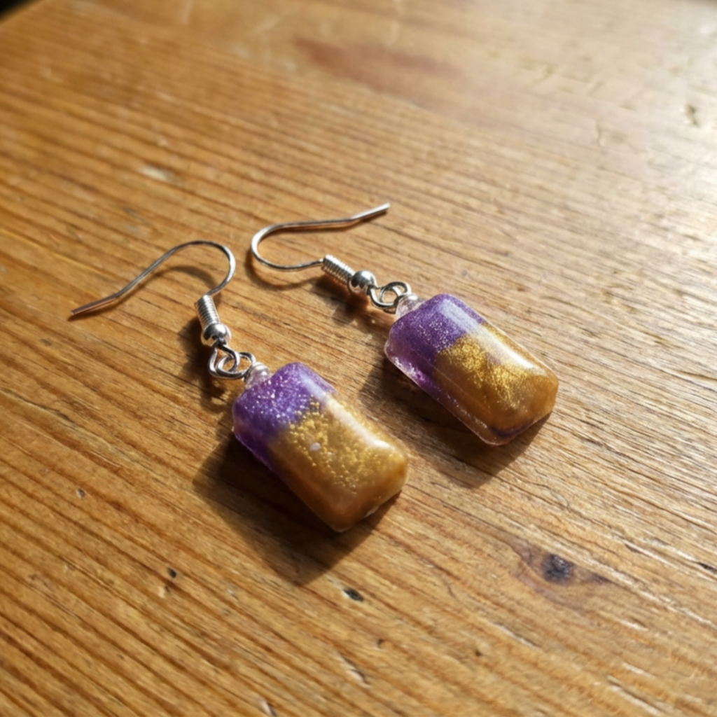 Striking small colour dangle earrings purple and gold rectangles on a wooden surface