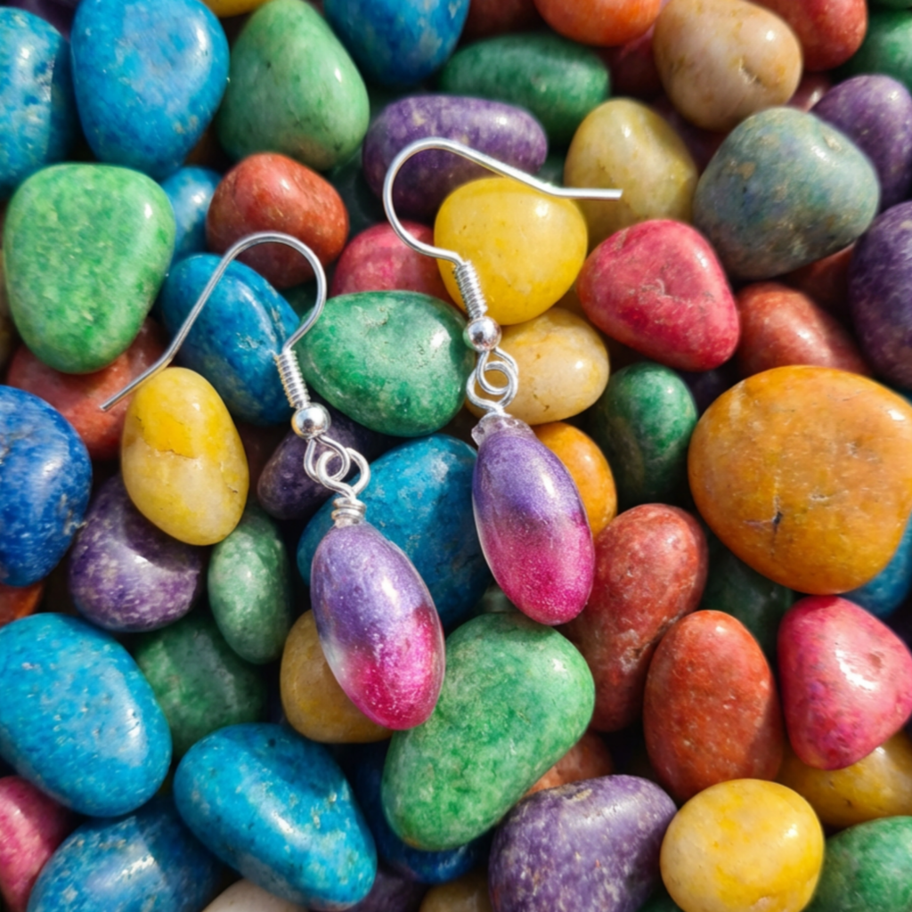 Colorful stone earrings on a background of multicolored stones