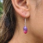 Model wearing a pair of oval pink and purple drop earrings