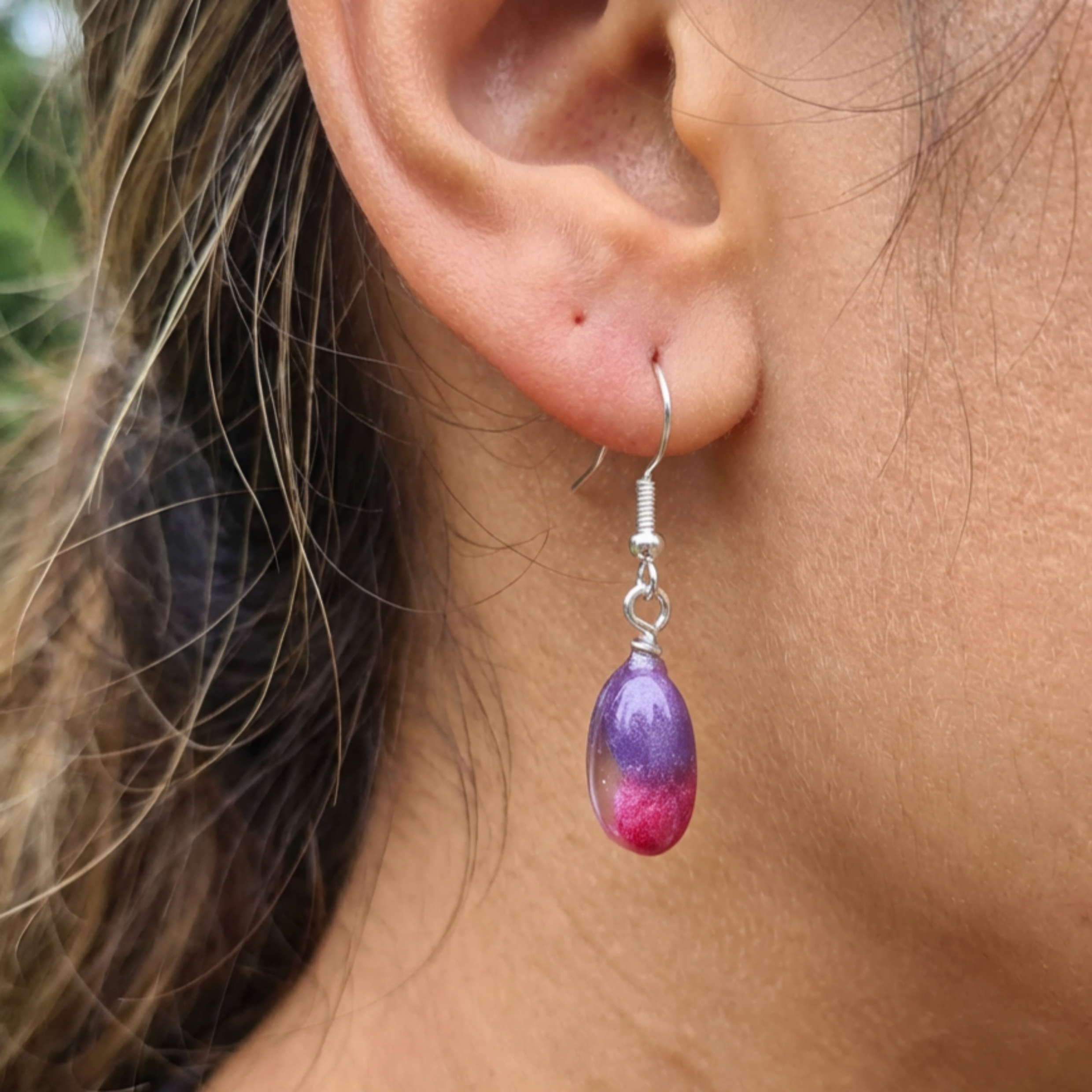 Model wearing a pair of oval pink and purple drop earrings