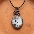 Necklace with a pendant featuring a white stone and copper wire wrapping on an orange background