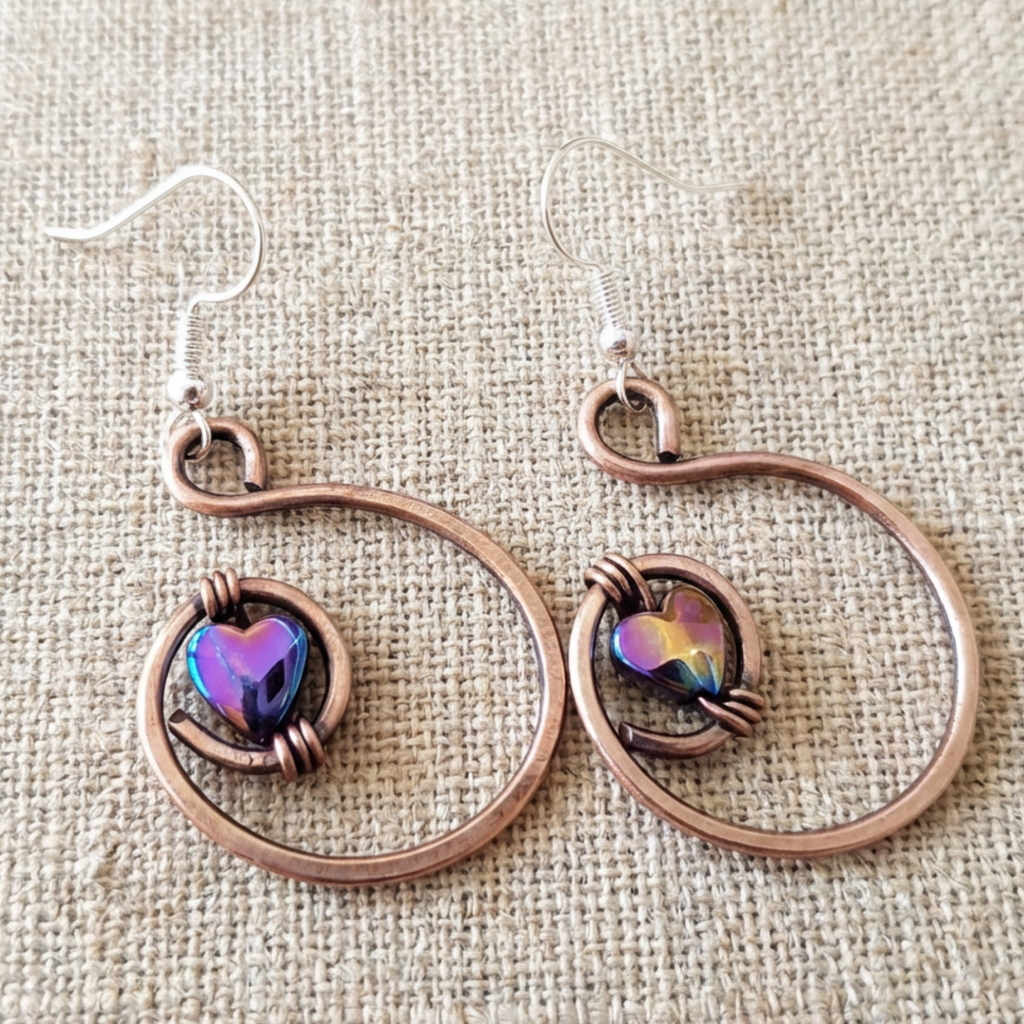 Rainbow hematite heart hoop copper earrings close-up, wire-encased hematite heart handmade UK