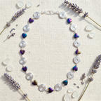Necklace with heart-shaped beads  and silver spirals on a textured surface with lavender flowers