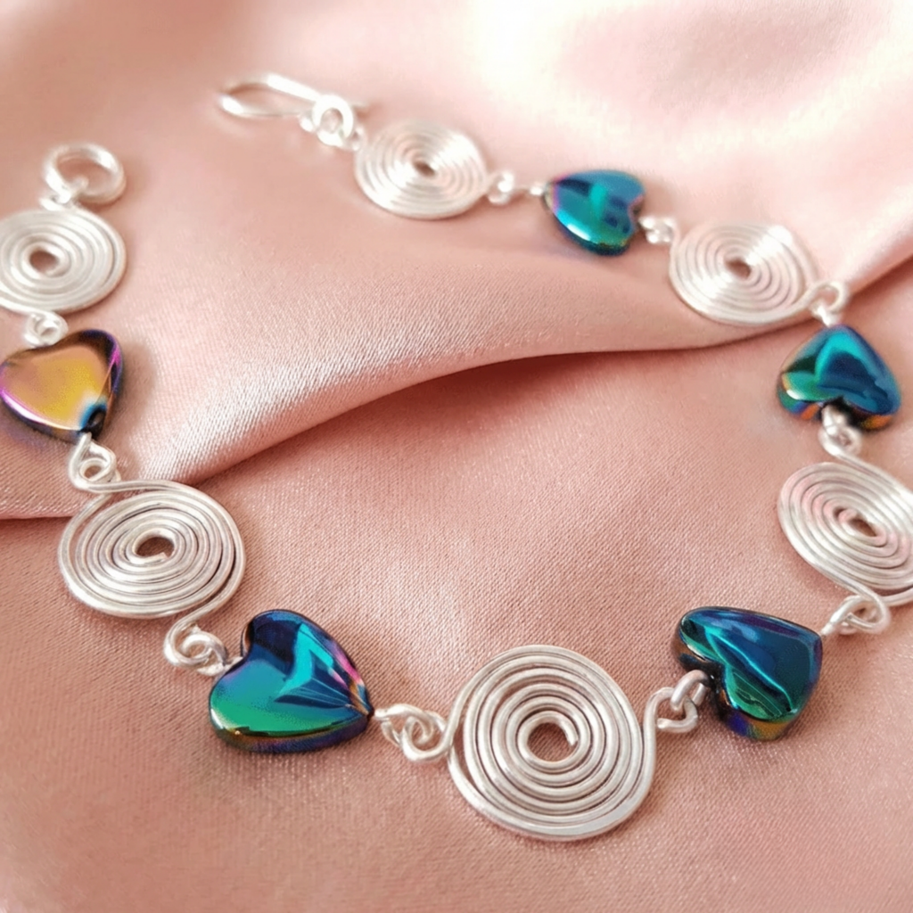 Silver bracelet with heart-shaped gemstones on a pink fabric background