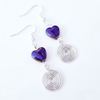 Earrings with purple heart-shaped beads and silver spiral designs on a white background