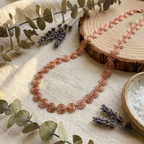 Copper necklace on a wooden surface with eucalyptus and lavender