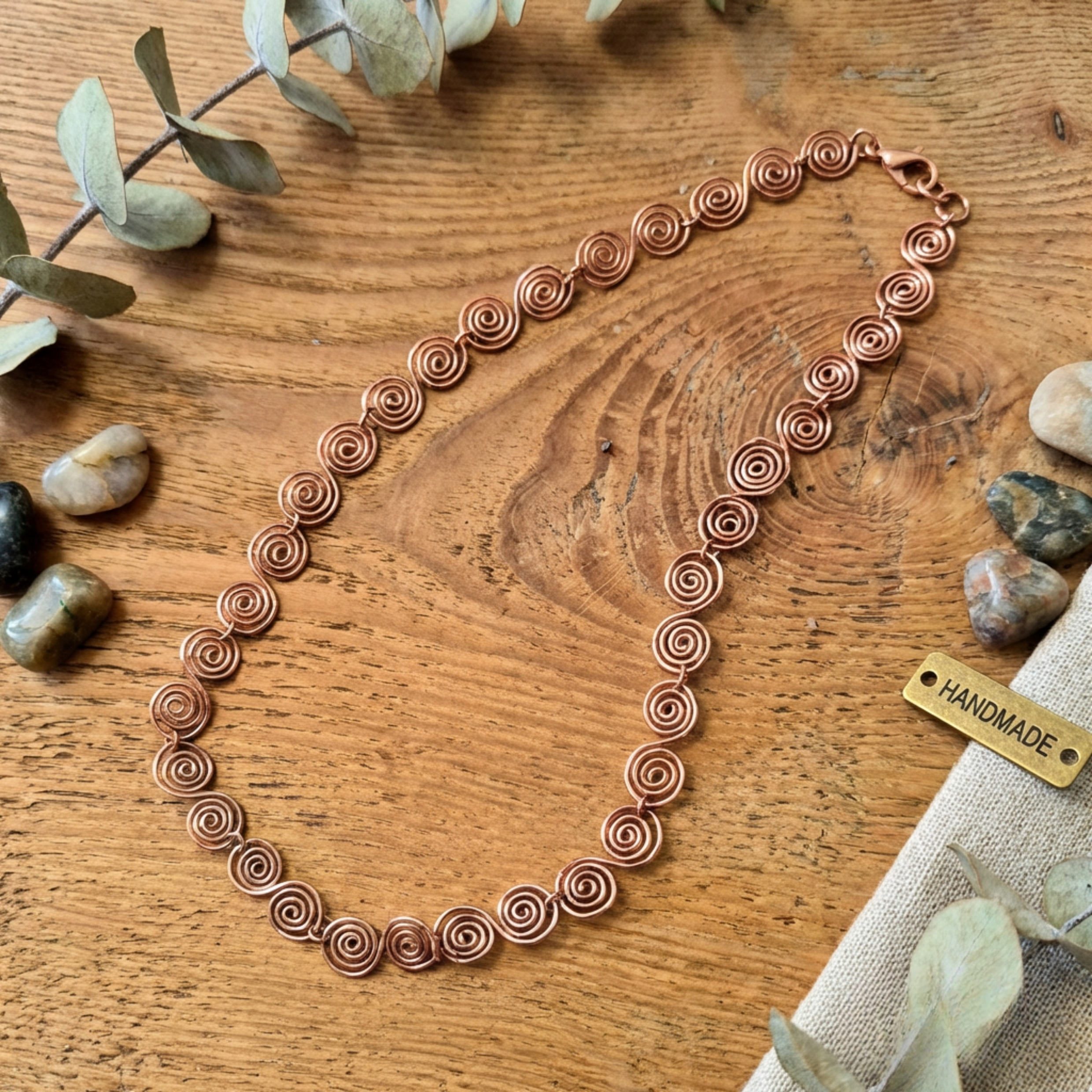 Copper necklace on a wooden surface with a 'Handmade' tag