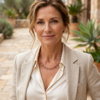 Woman wearing a beige blazer and white shirt with a Celtic copper necklace, standing outdoors.