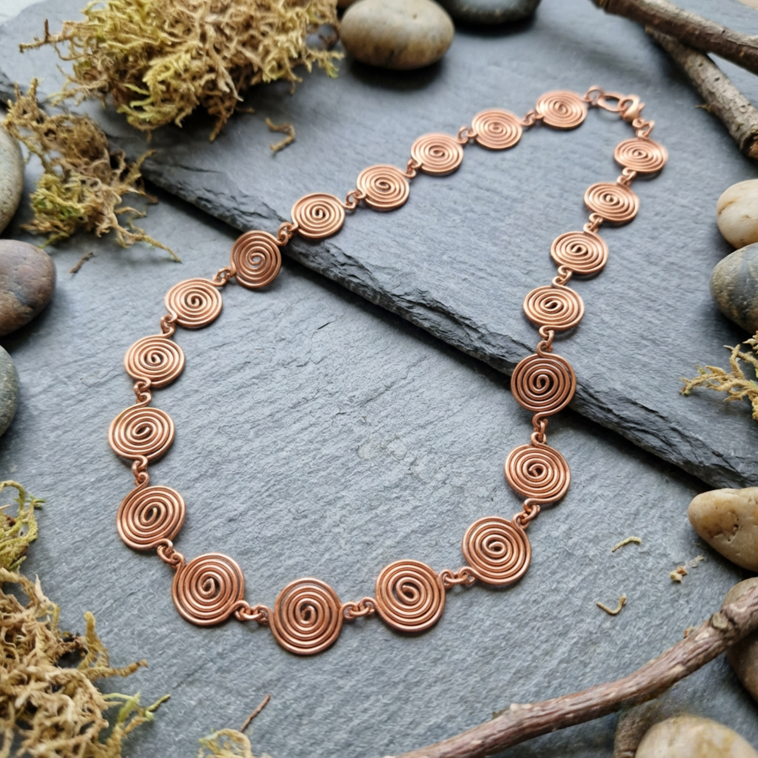 Copper necklace with circular design on a stone surface with natural elements