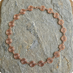 Copper necklace with circular links on a stone surface