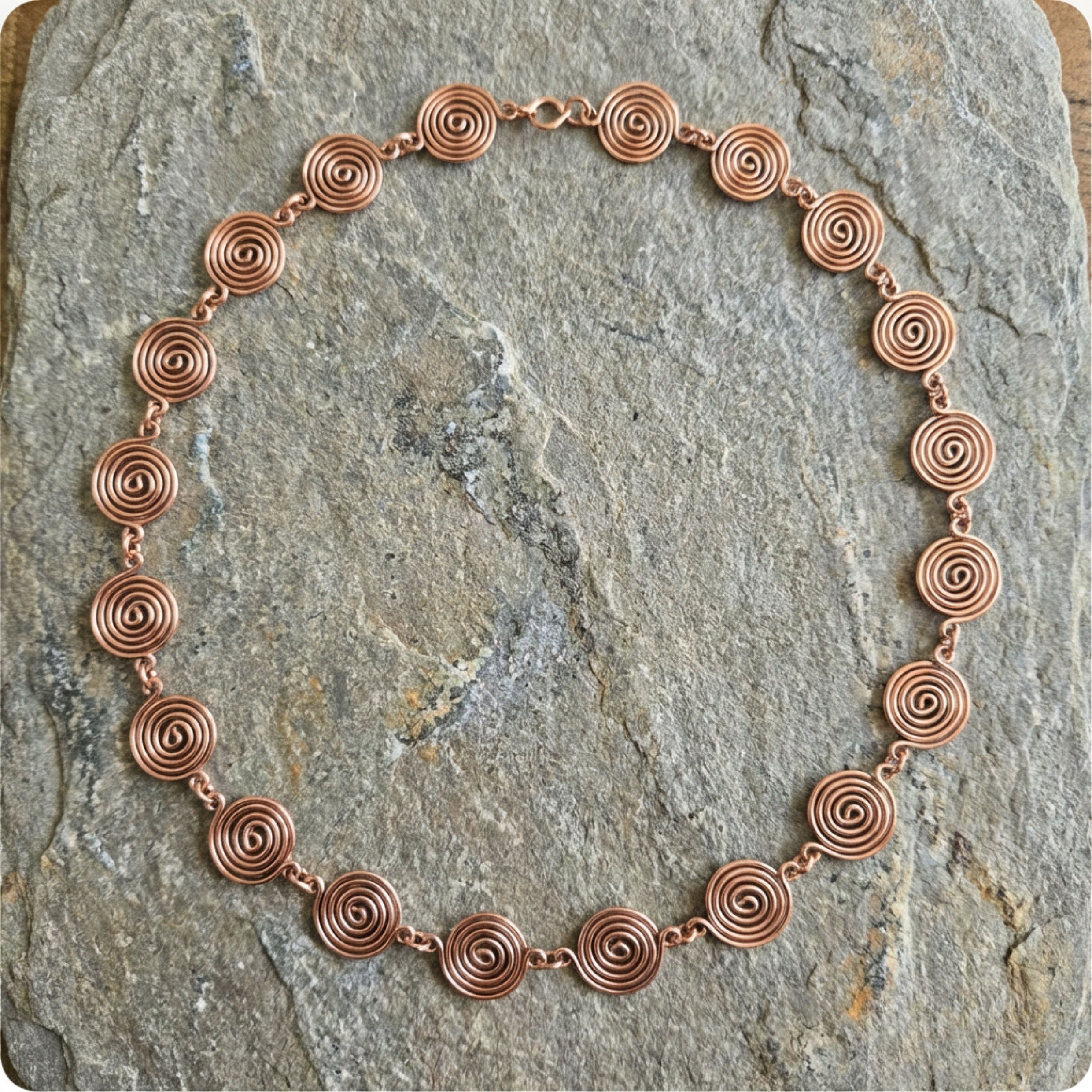 Copper necklace with circular links on a stone surface