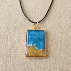 Necklace with a pendant featuring a blue and gold design on a beige fabric background