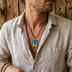 Man wearing a light-colored shirt with a necklace featuring a blue pendant.