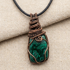Green stone pendant with copper wire wrapping on a beige fabric background