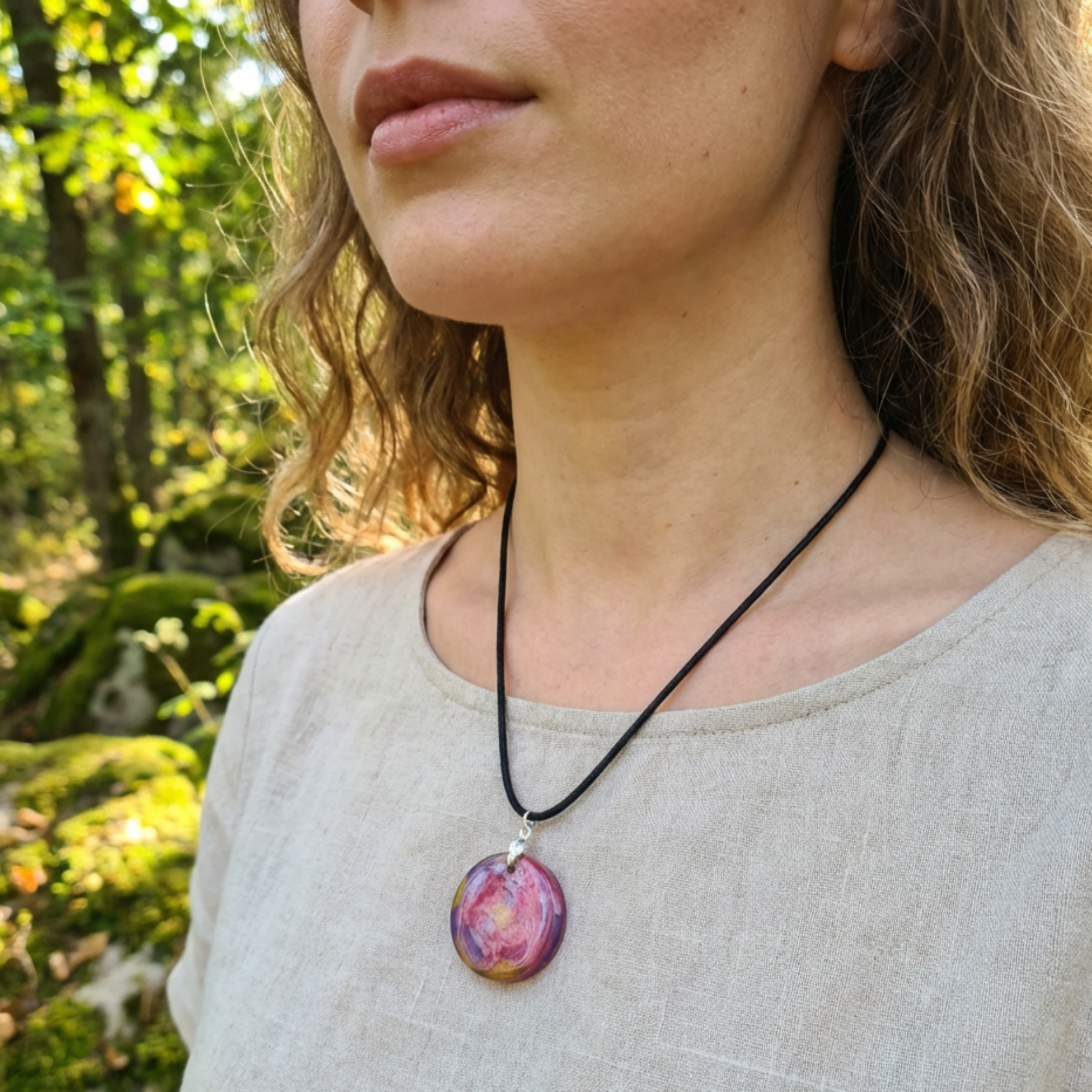 Woman wearing a necklace with a colorful pendant in a forest setting
