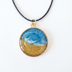 Necklace with a round pendant featuring blue and gold design on a white background