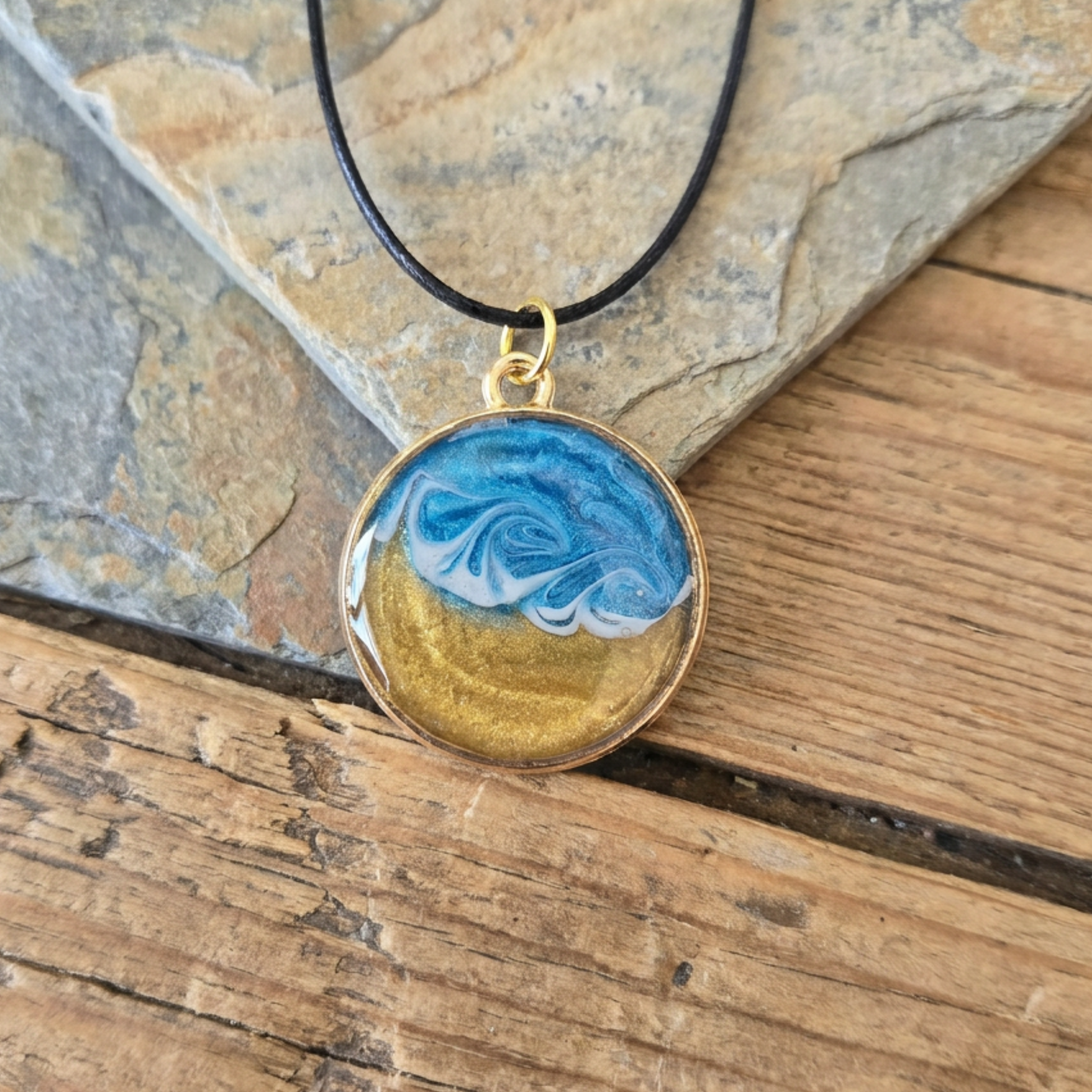 Necklace with a pendant featuring blue and gold design on a wooden surface