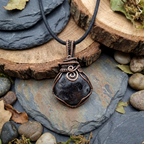 Necklace with a dark stone pendant on a natural stone surface
