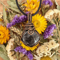 Necklace with a black stone pendant surrounded by dried flowers on a wooden surface