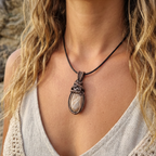 Necklace with a pendant worn by a person with wavy hair, against a neutral background.