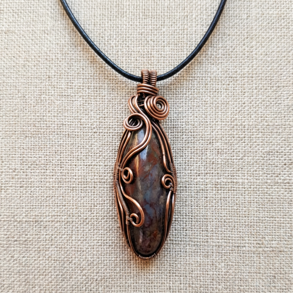 Copper gemstone pendant necklace on a beige fabric background