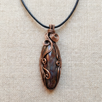 Copper gemstone pendant necklace on a beige fabric background