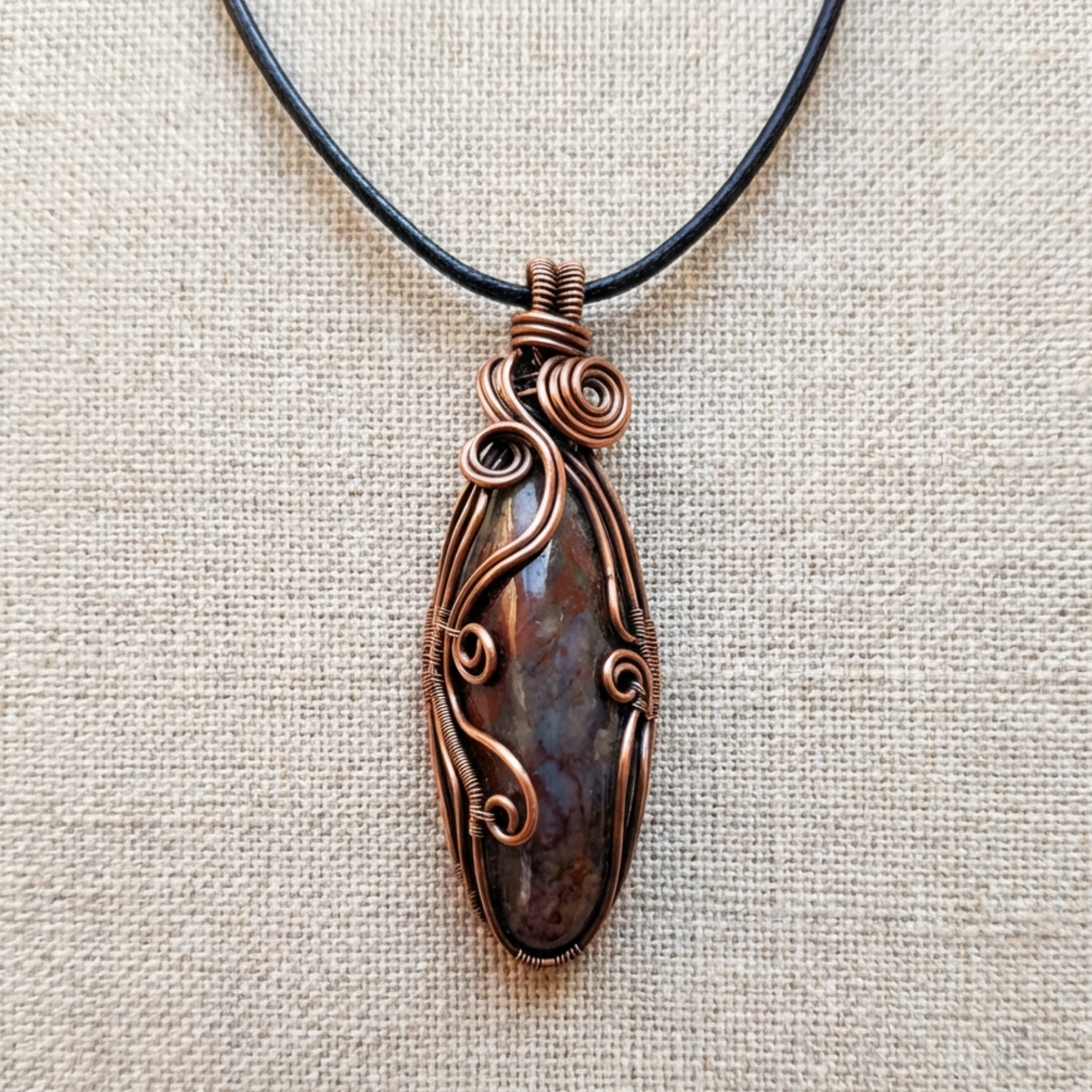 Copper gemstone pendant necklace on a beige fabric background