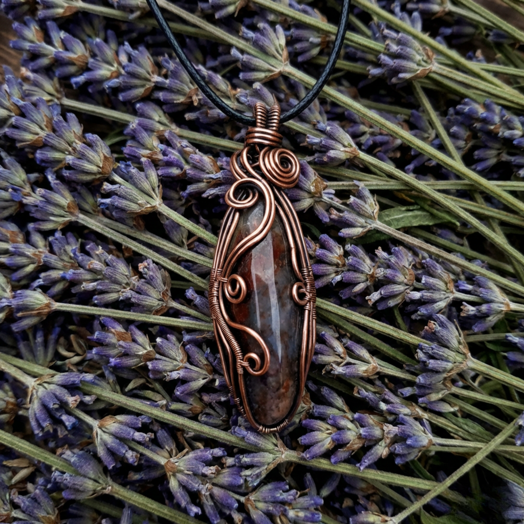 Copper wire-wrapped pendant on a black cord with lavender flowers in the background