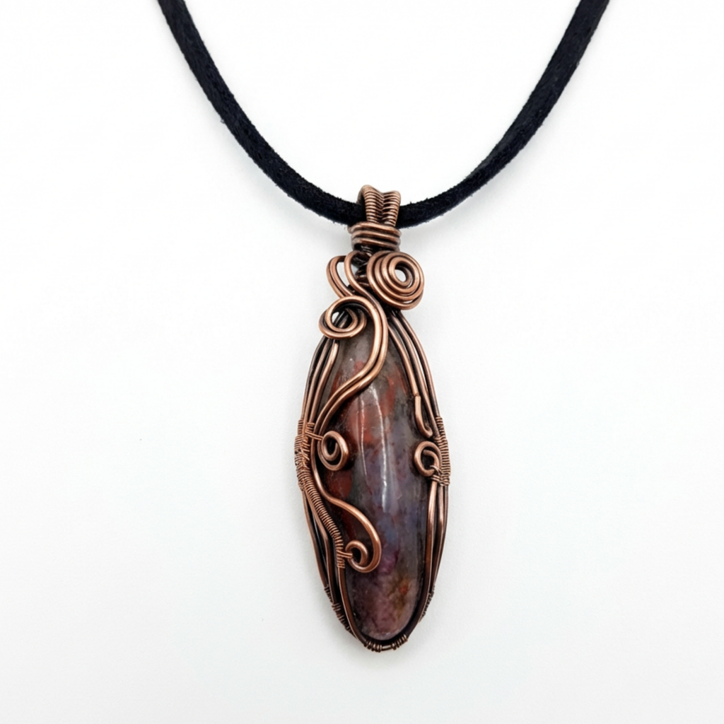 Copper-wrapped pendant with a Seftonite stone on a black cord against a white background