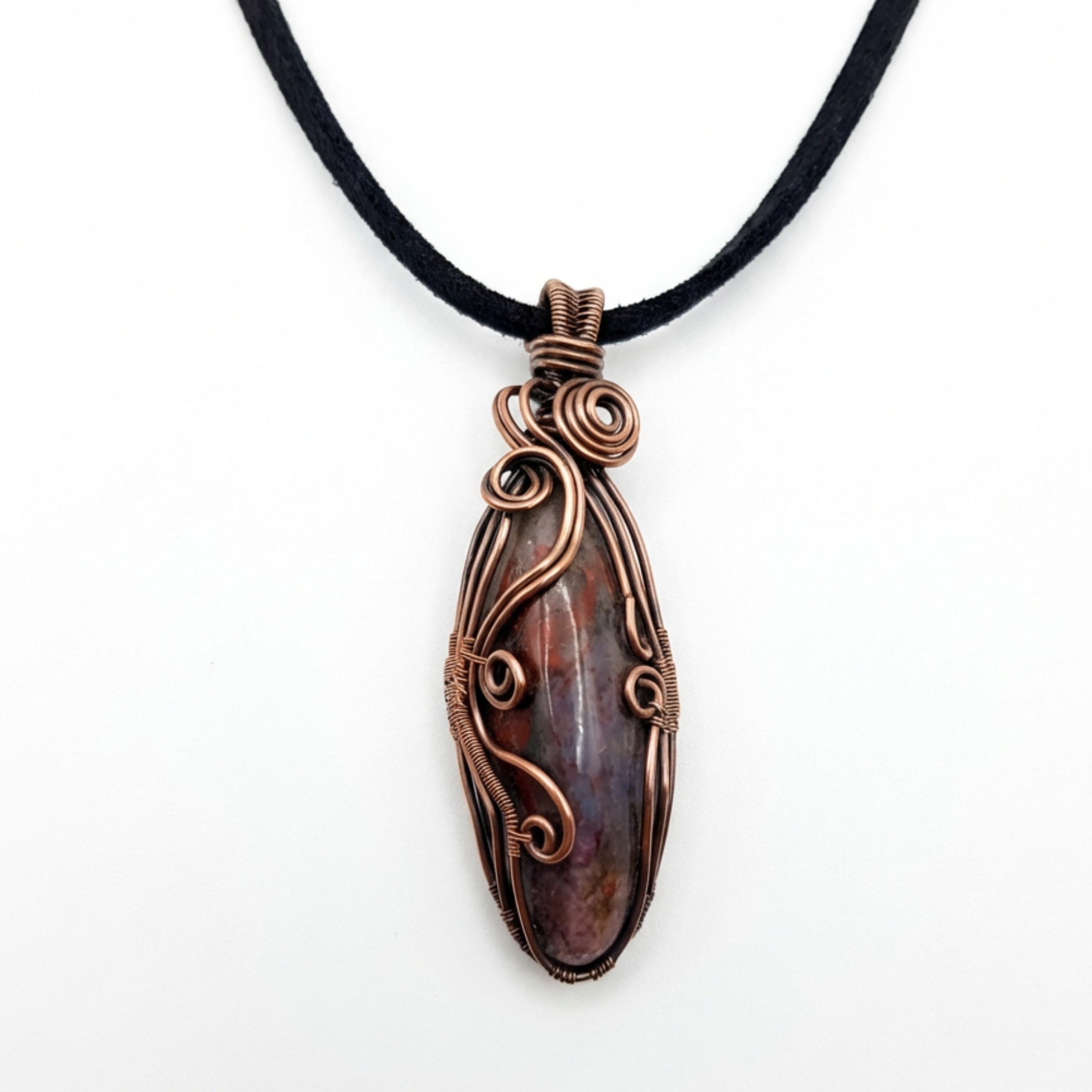 Copper-wrapped pendant with a Seftonite stone on a black cord against a white background