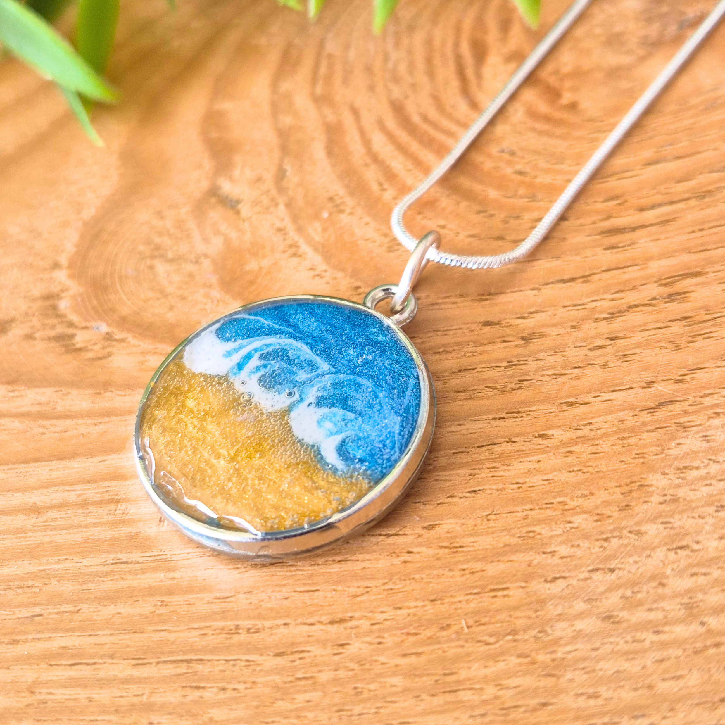 Round pendant with blue and gold design on a wooden surface