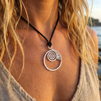 Femail model wearing a silver wire wrapped ammonite pendant on a black cord at the beach