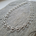 Silver heart-shaped necklace on a stone surface