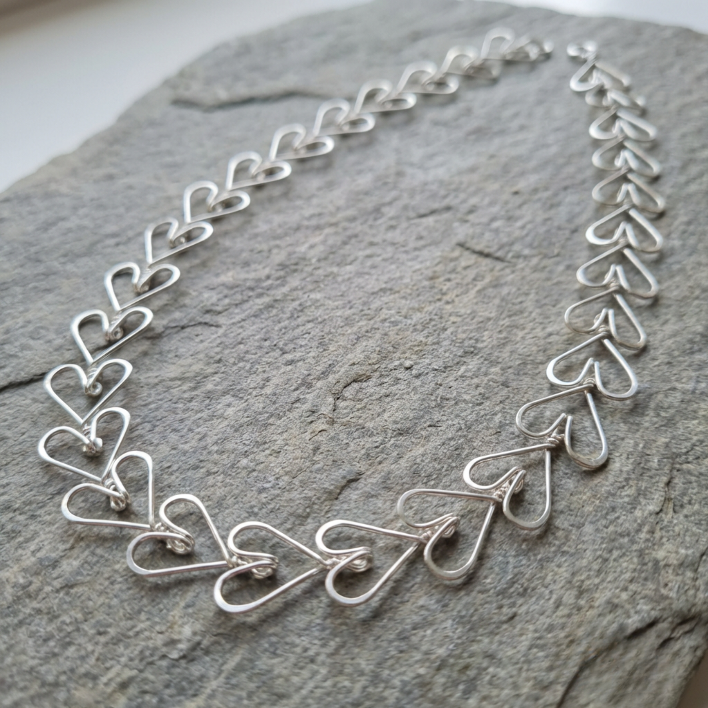 Silver heart-shaped necklace on a stone surface