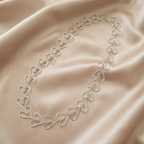 Silver heart-shaped necklace on a beige fabric background